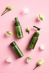 Wall Mural - Green cosmetic containers, flowers, ice cubes on pink background. Natural beauty products concept.