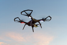 Close-up Of Black Drone, UAV, RPAs Flying In A Park At Sunset