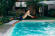 Little boy jumping in a pool. Child get fun in the swimming pool of his home. Outdoors activities in quarantine.