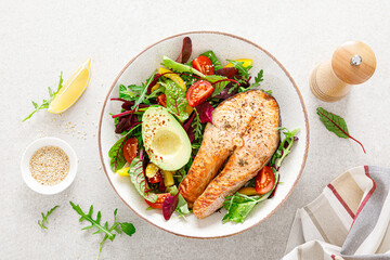 Wall Mural - Salmon fish steak grilled, avocado and fresh vegetable salad with tomato, bell pepper and leafy vegetables. Top view