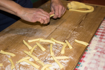 italian woman making pasta in the kitchen on wooden table on background. Female hands. Concept of homemade food.