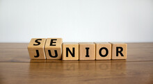 From Junior To Senior Symbol. Turned Cubes And Changed The Word 'junior' To 'senior'. Beautiful Wooden Table, White Background, Copy Space. Business And Junior Or Senior Concept.