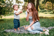 © zadorozhna - Mother with son blowing soap bubbles in the park.
