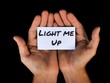 © Ekahardiwito - Man holding white paper in palm with text LIGHT ME UP. Motivational concept.