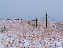 Barbwire Fence Through Snow Covered Desert 
