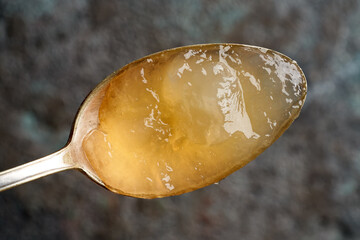 Wall Mural - Chilled congealed beef bone broth on a metal spoon, top view