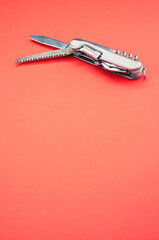 Poster - Vertical isolated shot of the multifunctional pocket knives on a pink background