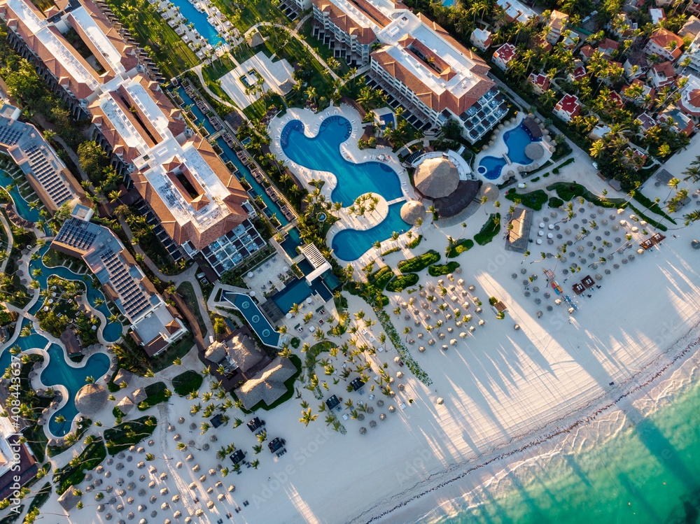 Aerial drone view of beach resort hotels with pools, umbrellas and blue water of Atlantic Ocean, Bavaro, Punta Cana, Dominican Republic - obrazy, fototapety, plakaty 