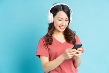 The beautiful Asian woman is using electricity while listening to music with white wireless headphones