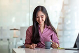Fototapeta Panele - Beautiful asian woman happy to drink coffee and play on the phone at desk office.