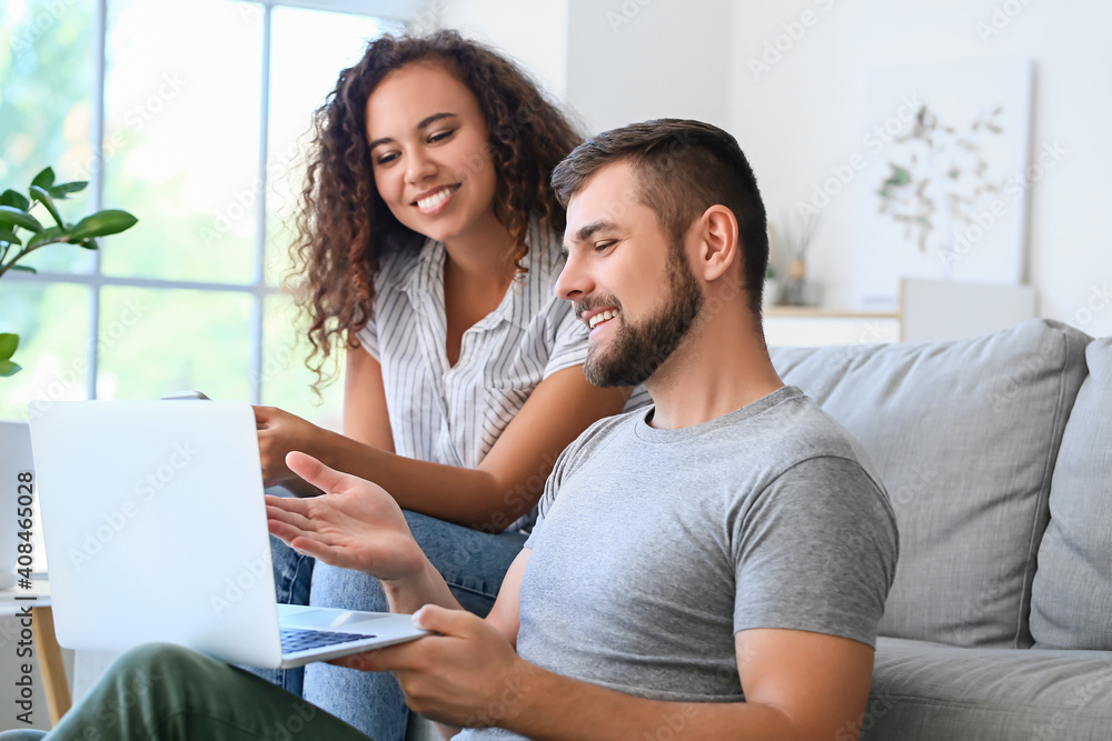 Young couple with gadgets relaxing on sofa at home