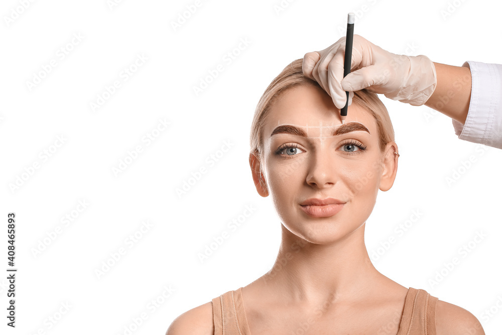 Young woman undergoing eyebrow correction procedure on white background