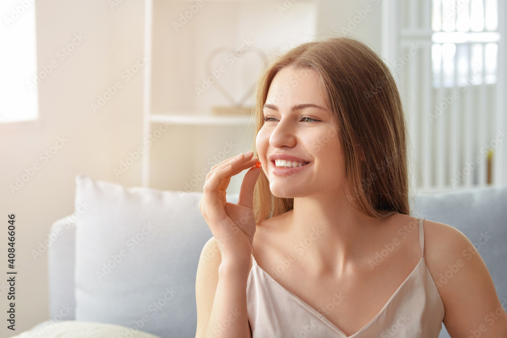 Beautiful young woman taking pills at home