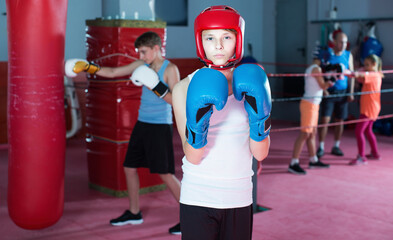 Wall Mural - Young serious teenager with boxing gloves posing at gym