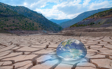 Poster - Global warming concept - Glass Globe (Planet Earth) on dry soil 