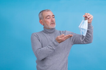 Wall Mural - adult man holding disposable medical mask in hand in virus and infection prevention