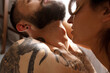 © Andrian - Beautiful loving couple Naked hug kissing in bed near the window in the morning . Romantic intimate lifestyle Love story of shirtless tattooed strong beard man with a sensual woman in loft apartment