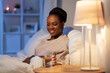 people, bedtime and thirst concept - happy smiling african american woman drinking water at home at night