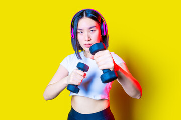 Fit young asian woman boxing on yellow background