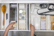 Top View Of Woman Hands Neatly Organizing Bathroom Amenities And Toiletries In Drawer In Bathroom.