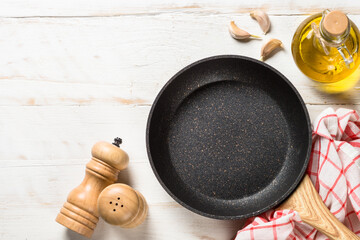 Wall Mural - Frying pan or skillet with sea salt and pepper on white wooden table. Top view with copy space.