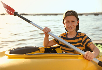 Poster - Happy little boy kayaking on river. Summer camp activity