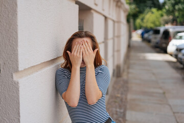 Wall Mural - young woman hides her face behind her hands