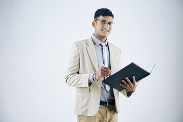 Wall Mural - studio portrait of handsome young indian businessman taking notes in document