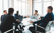 Group of young business people working and communicating while sitting at the office desk together with colleagues sitting. business meeting