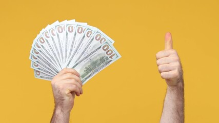 Wall Mural - Cropped close up man male hand arm hold fan of cash money in dollar banknotes showing winner gesture clenching fist celebrate isolated on yellow background studio. Copy space commercial promo mock up