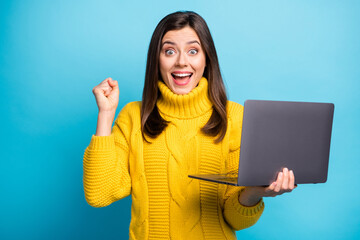 Sticker - Photo of adorable lucky young lady wear yellow sweater rising fist holding modern gadget isolated blue color background