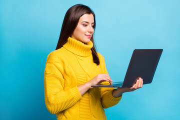 Poster - Profile side view portrait of lovely focused cheery girl holding in hands using laptop typing isolated over shine blue color background