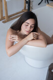 Fototapeta Na drzwi - Brunette caucasian adult woman lay in bath relaxing. Sensual sexy portrait at home