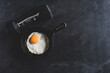 Dumbbell with fried egg in a pan on dark background with copy space