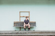 © Cavan Images - Teenage boy sitting alone on a wooden bench seat
