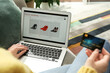 © New Africa - Woman with credit card using laptop for online shopping at home, closeup