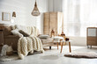 © New Africa - Cozy living room interior with beige sofa, knitted blanket and cushions
