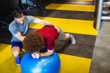 Wall Mural - Fat young men with trainer exercising at fitness gym.