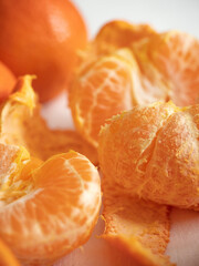 Wall Mural - Fresh juicy bright orange tangerines with green leaves on a white cotton tablecloth in the morning light