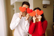 © maxbelchenko - Happy couple huging and holding red hearts over eyes. Valentine’s Day, celebration, love and romance.