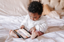 Mixed Race African Black Toddler Baby Girl Watching Cartoons On Tablet. Ethnic Diversity. Little Kid Child Using Technology. Early Age Education Development. Video Chat Or Video Call.