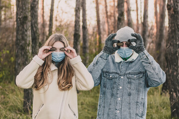 A guy and a girl in medical masks in a pine forest