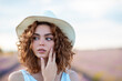 © Cavan Images - curly-haired woman with a hat outdoors