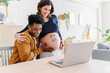 © Cavan Images - Husband and pregnant wife celebrating ultrasound results in front of a laptop, with a phrase written on her belly that it is a girl. Parenthood concept