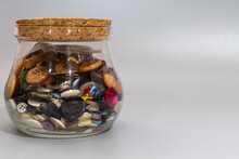 Glass Jar With Cork Top Holding An Assortment Of Colorful Sewing Buttons