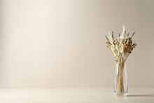 Dried Flowers In Vase On Table Against Light Background. Space For Text
