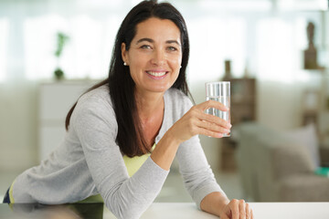 happy woman is drinking water at home