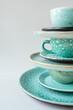 © Hanna - Vertical composition from a handmade turquoise plate and mug on gray background.