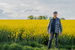 © volf anders - Portrait of Successful Farmer Examining Crops at Agriculture Field. Farmer Looking at Crops Oilseed Field