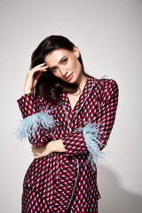 Pretty sexy woman beautiful face natural makeup brunette hair wear silk textile suit pants and blouse with feathers shoes comfort casual home dress luxury lifestyle pajama party glamour fashion model.